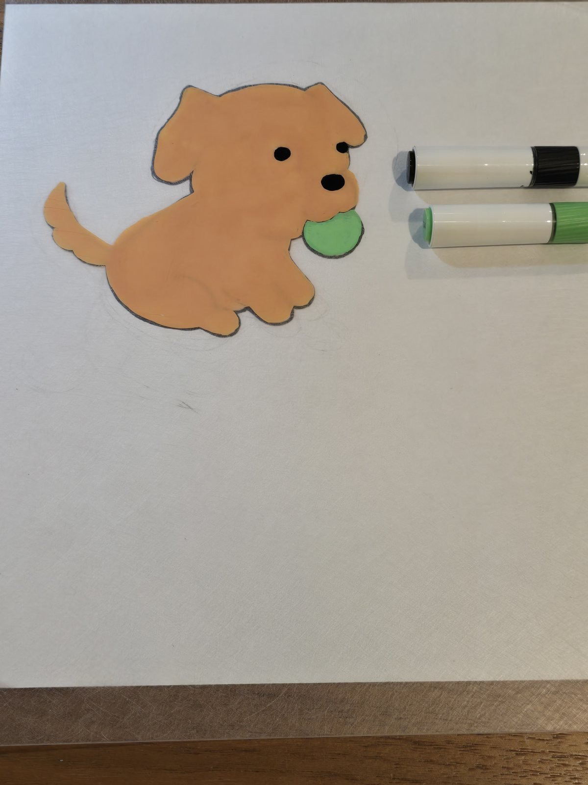 The fully colored design on shrink plastic, with the acrylic markers used laid beside it
